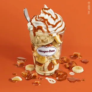 a cup of ice cream with bananas, caramel, and pretzels