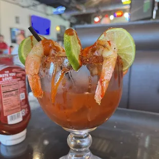 a bloody cocktail with shrimp and lime garnish