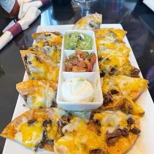 a plate of nachos with dips