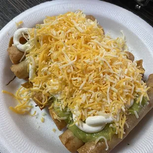 6 Beef taquitos with guacamole, sour cream and cheese.