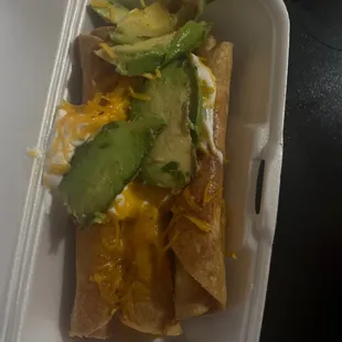 The side of a full avacado i ordered on top of rolled tacos
