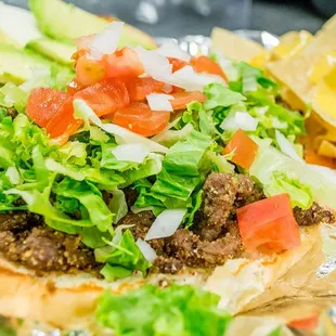 a taco sandwich with lettuce, tomato, and cheese