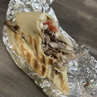 Half eaten beef shawarma, added garlic sauce.