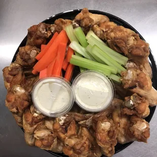 a platter of chicken wings, carrots, celery, and ranch dressing