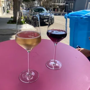 two glasses of wine on a pink table
