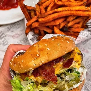 a hand holding a burger and french fries