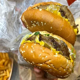 a hand holding two hamburgers