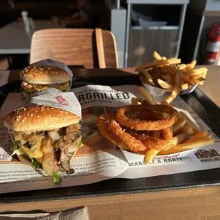 My mushroom bacon cheeseburger &amp; half onion rings/half fries. My wife's order in the back round.