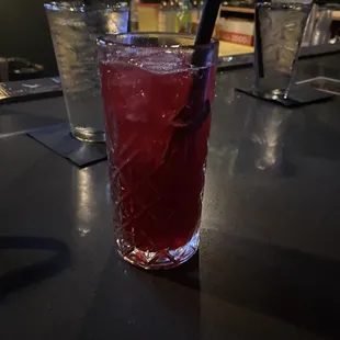 a glass of red drink with a straw