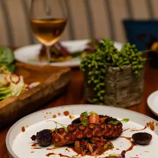 a wooden table with plates of food and a glass of wine