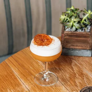 a cocktail in a coupe glass on a wooden table