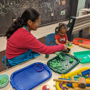 Art Studio staff making homemade play dough creations with a young girl