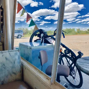 Inside the helpful HACHITA FOOD MART rest/recuperation area, viewing my recharging eBikeKit-assisted CruzBike--awaiting 4 new spokes!