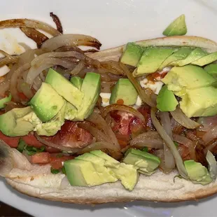 a hot dog with avocado and onions