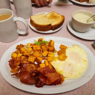 Over medium eggs, home fries, bacon, white toast, and grits on the side