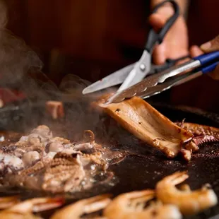 a person cutting meat on a grill