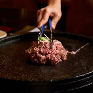 a person cutting a steak on a grill