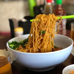 a bowl of noodles with chopsticks