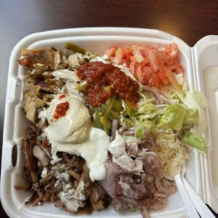 Beef and chicken shawarma player on rice with garlic sauce, hummus, and all the greens.