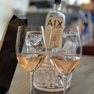 two glasses of wine and a bottle of ax