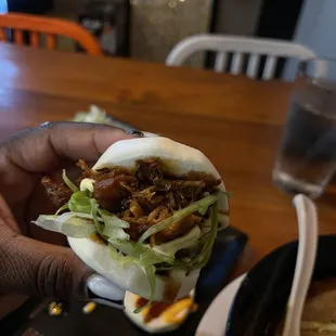 a person holding a bun with meat and lettuce