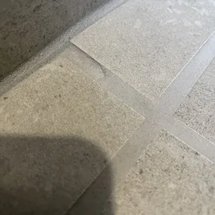 Uneven tile and grout. Messy seams.