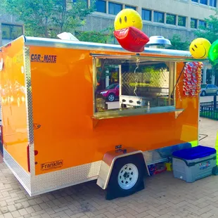 an orange food truck with a smiley face on top