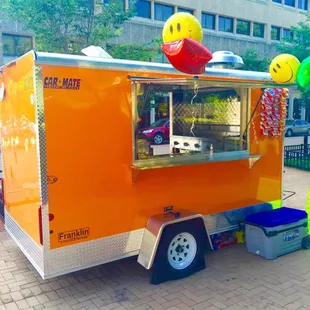 an orange food truck with a smiley face on top