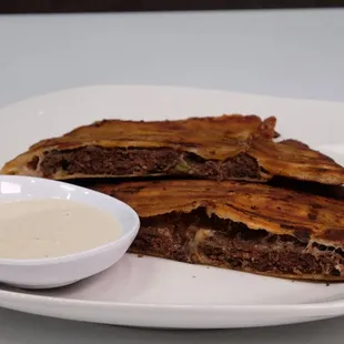 Hawawshi (Egyptian pita bread stuffed with kebob meat, mozzarella cheese and spices, cooked and served with tahini sauce.