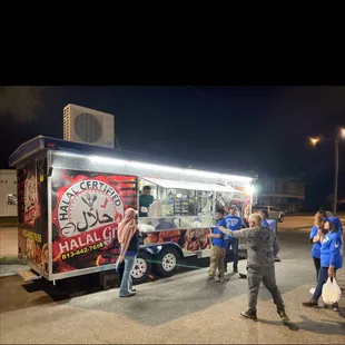 a group of people standing in front of a food truck