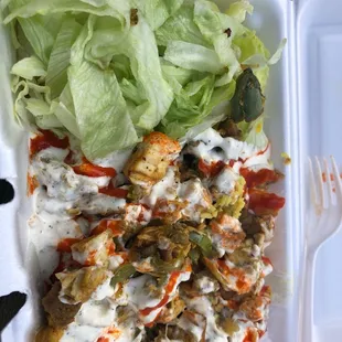 a takeout container with a salad and chicken