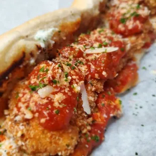 a meatball sandwich with tomato sauce and parmesan cheese