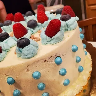a white cake with blue frosting and raspberries