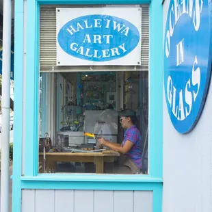 Woman in the window sculpting glass.