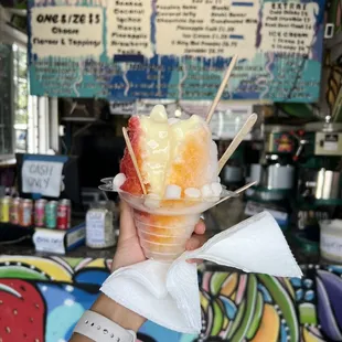 a hand holding a cup of fruit