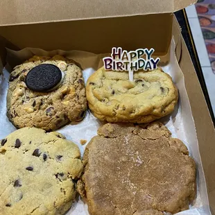 a box of cookies with a happy birthday candle