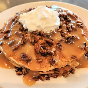 a stack of pancakes with caramel sauce and pecans