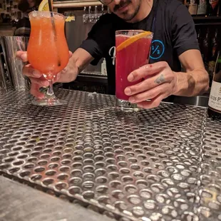 a man at a bar with two cocktails