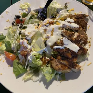 a plate of salad with chicken and dressing