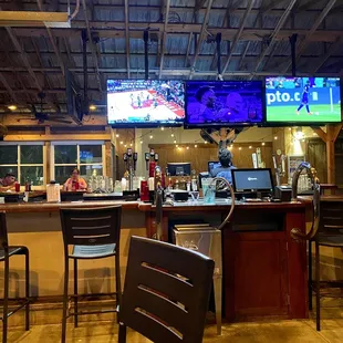 a bar with chairs and televisions
