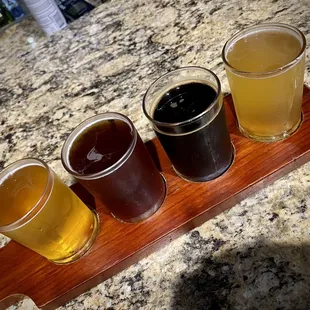 four glasses of beer on a wooden tray
