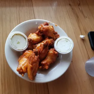 a plate of chicken wings with dipping sauces
