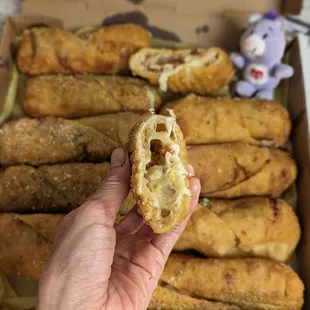 a hand holding a half eaten pizza