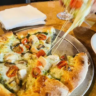 a person taking a slice of pizza