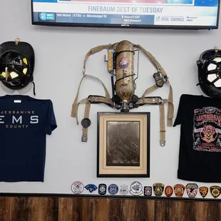 helmets, t - shirts, and other items displayed on a wall