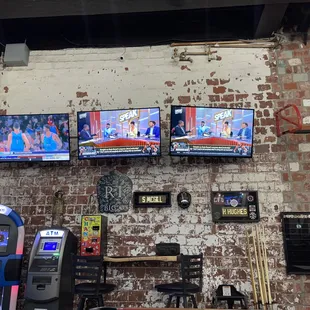a brick wall with three televisions mounted on it
