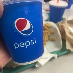 a person holding a pepsi cup