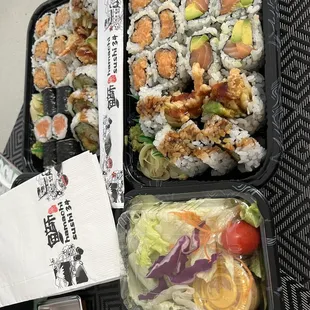 a tray of sushi and salad
