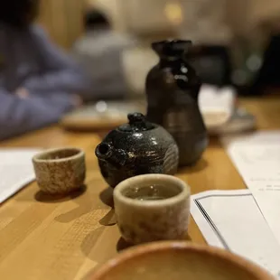 a woman sitting at a table with bowls and cups