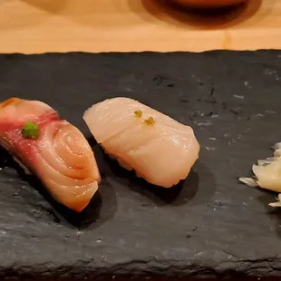 three pieces of sushi on a slate plate